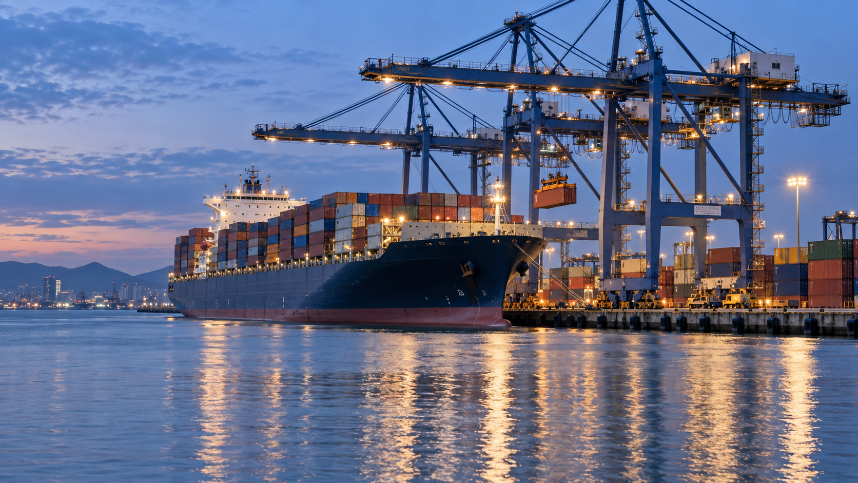 A container ship berthed at a modern deep water port with gantry cranes loading containers at dusk, calm water in the foreground, cool blue evening light, realistic documentary photography, 16:9 landscape